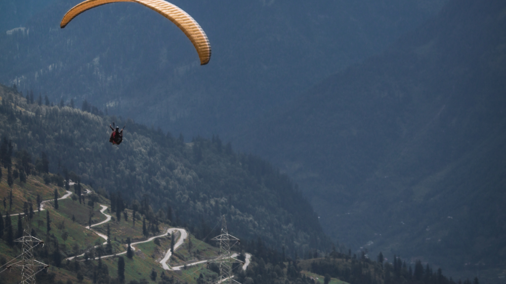 A person paragliding over a lush green hillside