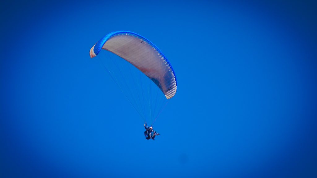 A paraglider soaring through a clear blue sky during Kamshet paragliding, showcasing the thrill and beauty of this adventurous activity.