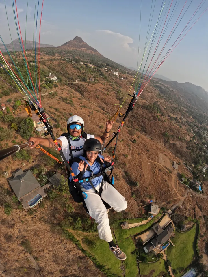 A guest and tandem pilot flying above the hills and village roads