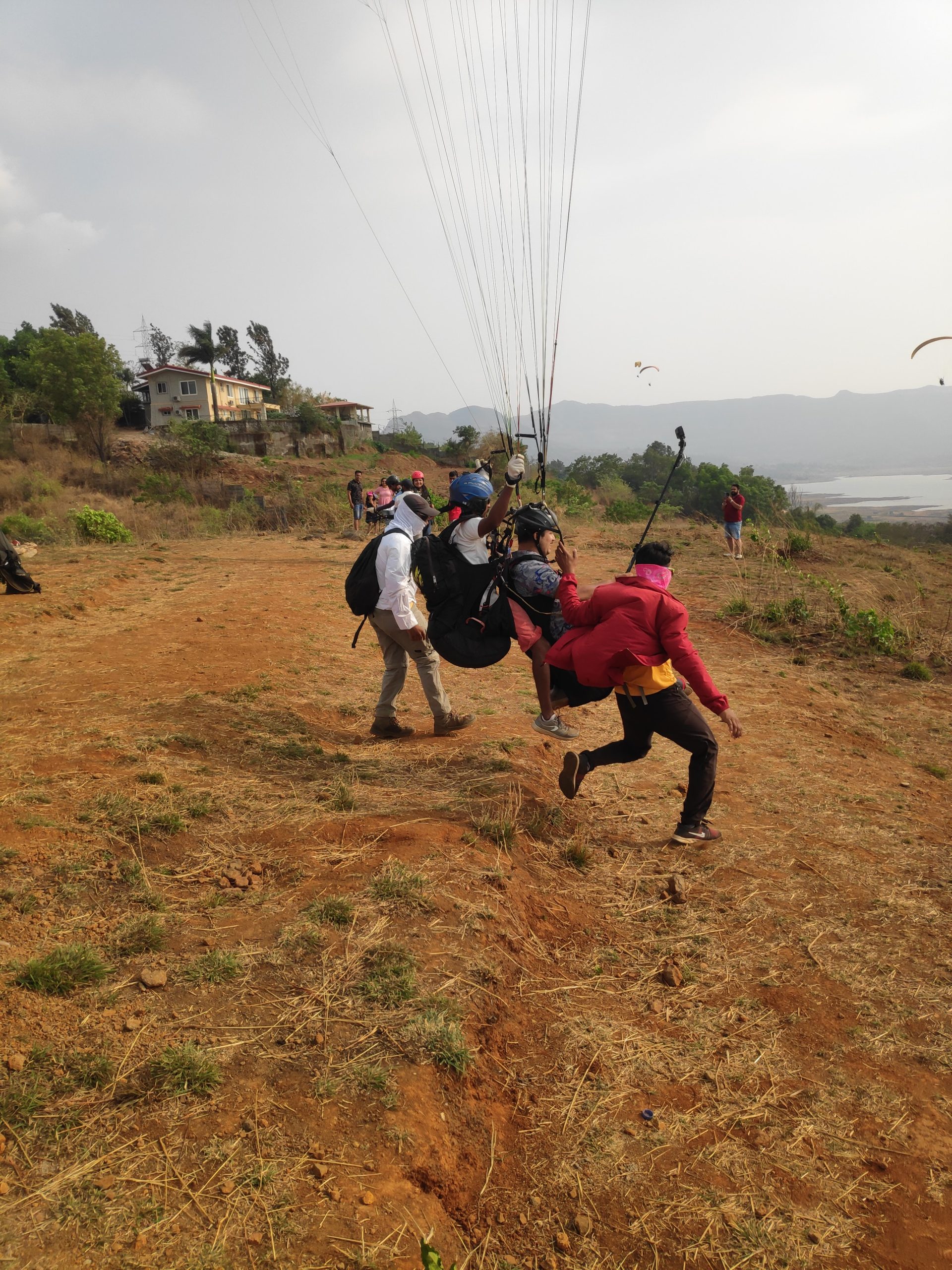 Group of paragliders preparing for takeoff in Kamshet, showcasing the scenic terrain and enthusiasm for adventure sports.